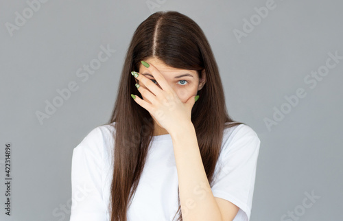 Young woman with hand on her face isolated on gray background, facepalm