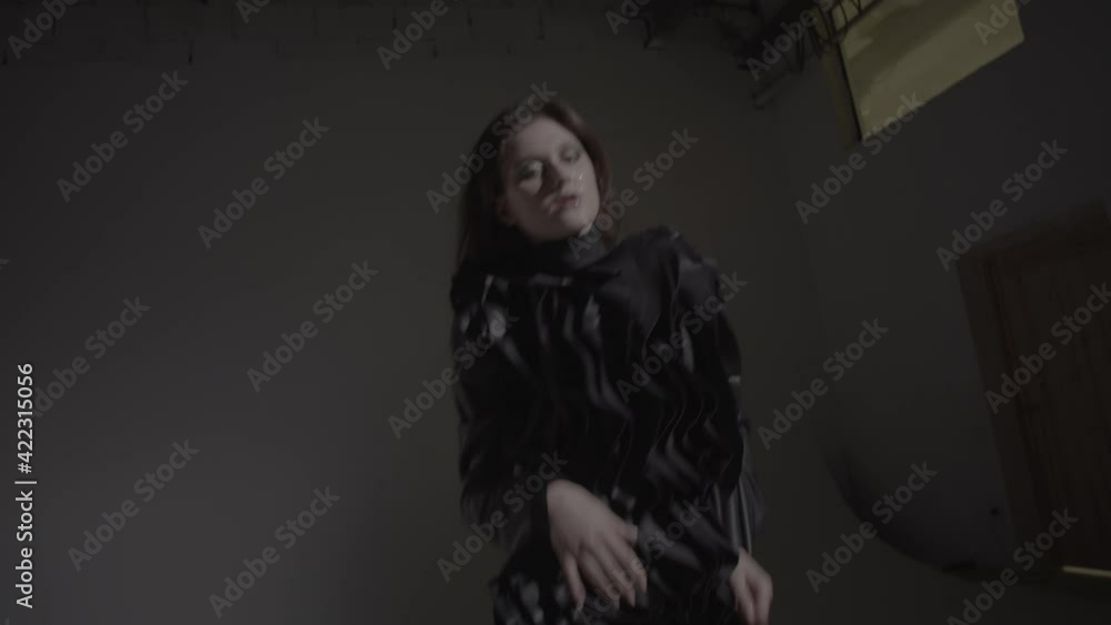 Dark hair woman posing in the black dress in the studio lights. Young attractive woman wearing a black dress. Ungraded video. Dark hair woman posing in the black dress in the studio lights. Young attractive woman wearing a black dress. Ungraded video.