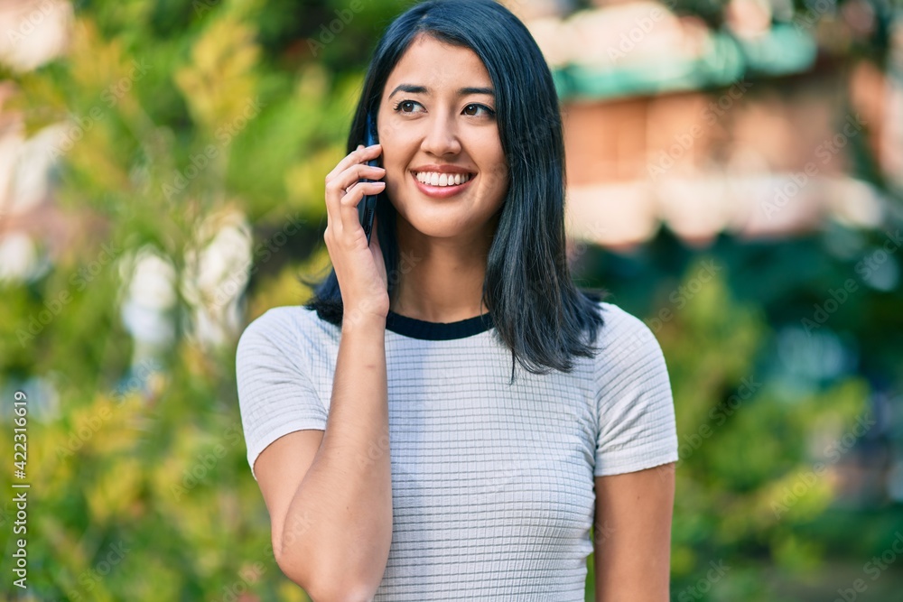 Young hispanic woman smiling happy talking on the smartphone at the city. Young hispanic woman smiling happy talking on the smartphone at the city.