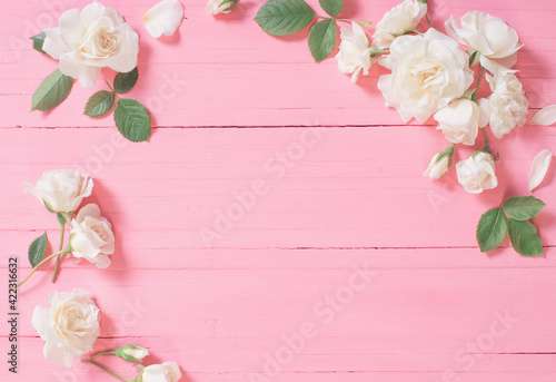 white roses on pink wooden background