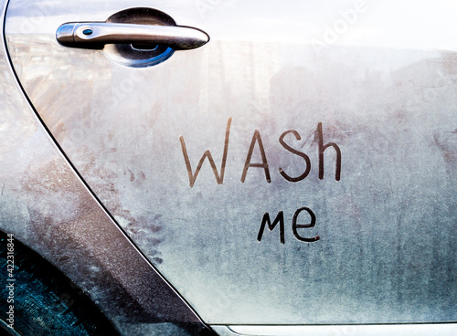 Dirty car with wash me words on door. Concept photo of car wash