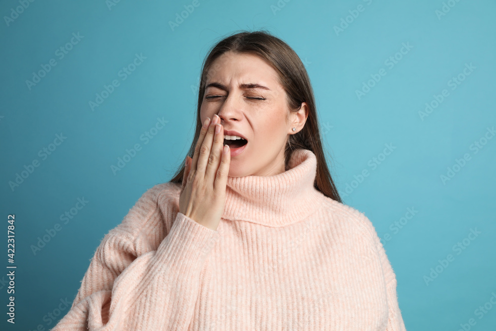 Young tired woman yawning on light blue background Young tired woman yawning on light blue background