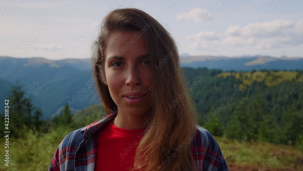Portrait of laughing woman face looking at camera in green mountains Portrait of laughing woman face looking at camera in green mountains