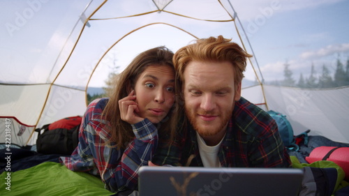 Woman and man looking on digital tablet screen. Girl covering guy eyes with hand