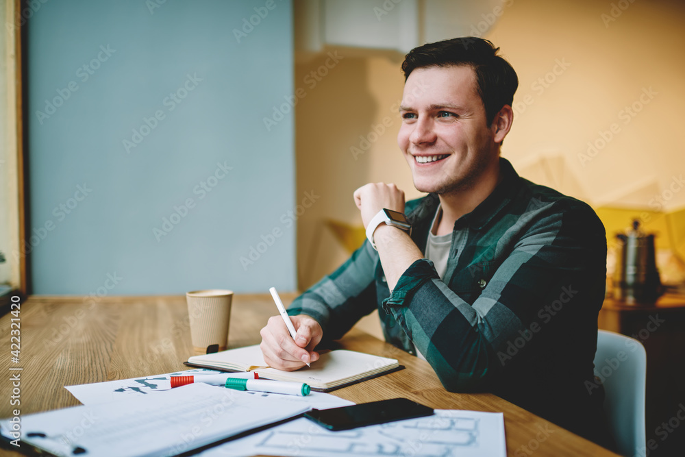 Cheerful man writing in diary plan for next day in cafe Cheerful man writing in diary plan for next day in cafe