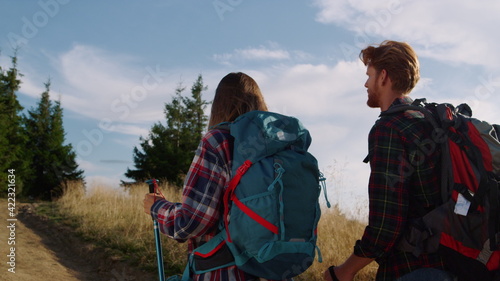 Hikers walking in summer mountains. Serious guy and girl talking together