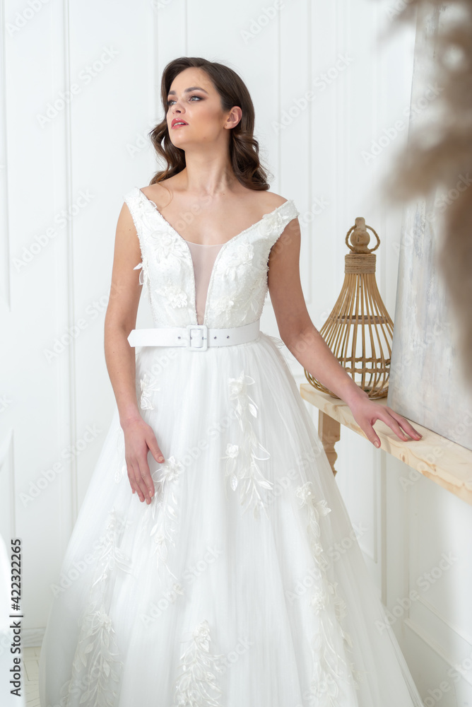 Bride in beautiful dress standing indoors interior at home. Trendy wedding style shot. Wedding makeup and hairstyle. Beautiful Bride in the morning. Bride in beautiful dress standing indoors interior at home. Trendy wedding style shot. Wedding makeup and hairstyle. Beautiful Bride in the morning.
