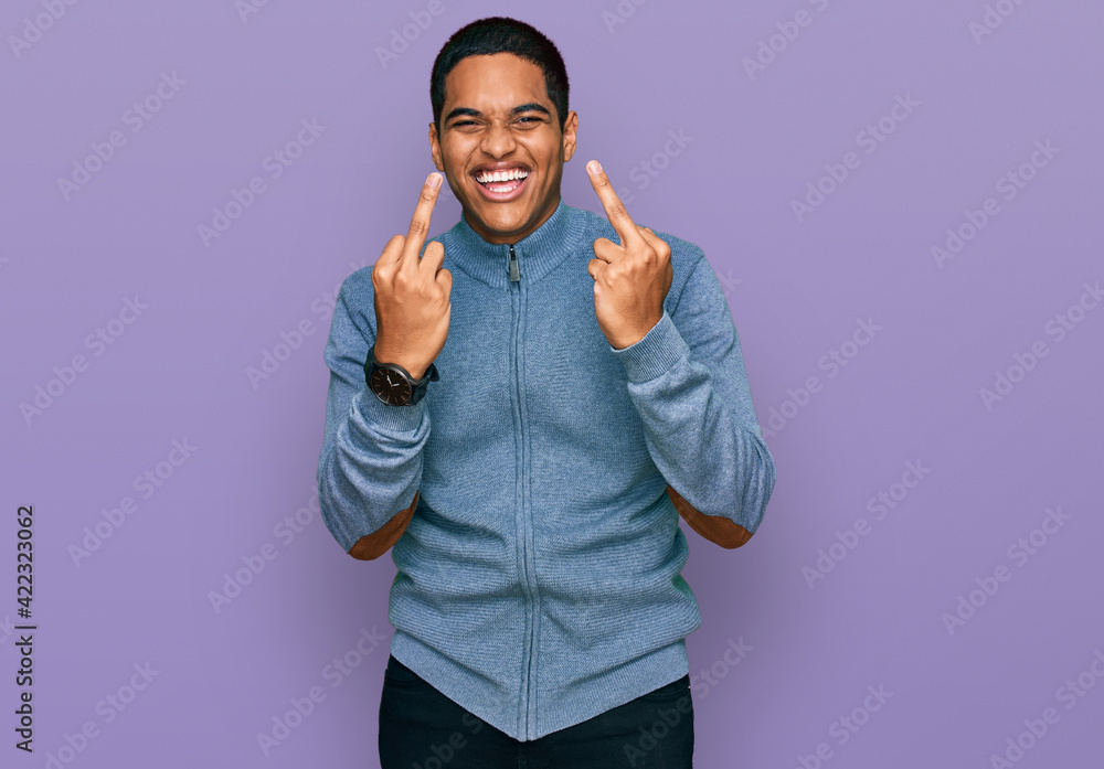 Fototapeta premium Young handsome hispanic man wearing casual sweatshirt showing middle finger doing fuck you bad expression, provocation and rude attitude. screaming excited