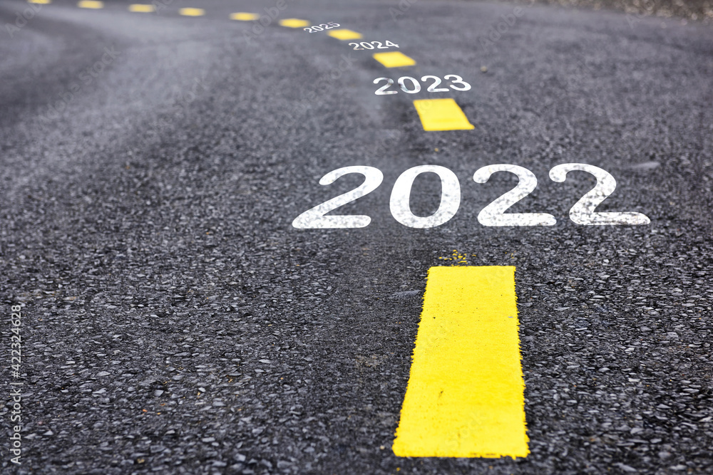 Obraz premium New year 2022 to 2025 on asphalt road with marking lines for giving directions. Business challenge concept and keep moving idea