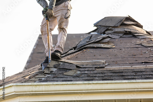 roofer removing roof nails with roof shingle remover