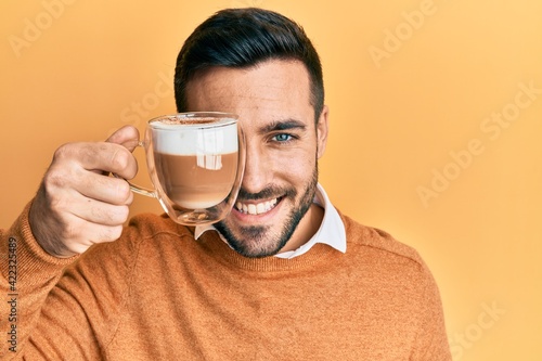 Wallpaper Mural Young hispanic man holding cup of coffee over eye looking positive and happy standing and smiling with a confident smile showing teeth Torontodigital.ca