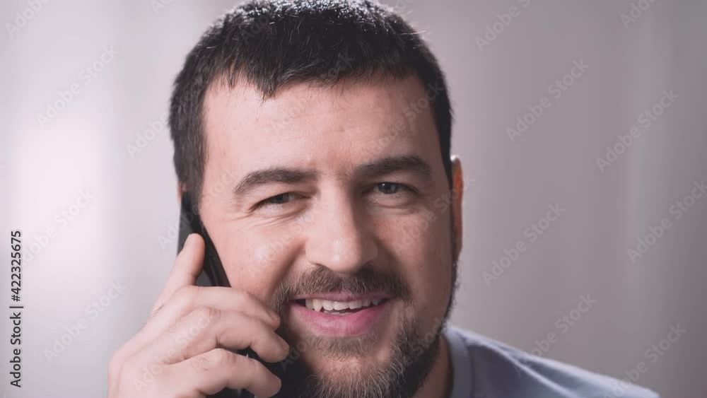Young handsome man talking mobile phone in the office or at home. Сheerful businessman having phone call at workspace. Closeup portrait of smiling man with smartphone. Young handsome man talking mobile phone in the office or at home. Сheerful businessman having phone call at workspace. Closeup portrait of smiling man with smartphone.