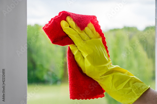 Washing windows. Woman in yellow rubber gloves wipes the glass. Housework concept.