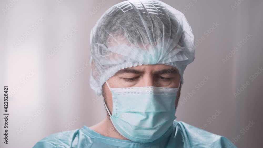 Male doctor in medical uniform wearing protective cap, face mask, and white gloves. Male hospital worker portrait in protective suit. Male doctor in medical uniform wearing protective cap, face mask, and white gloves. Male hospital worker portrait in protective suit.