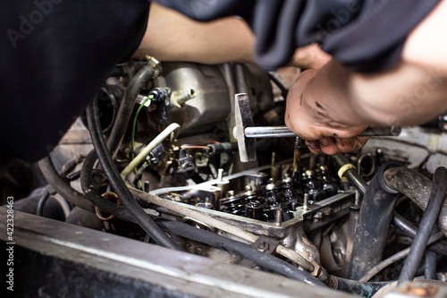 a mechanic performing diagnostics and repairs of a car, the front and background background is blurred with bokeh effect