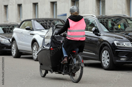 Konstfotografi frau mit helm und schutzweste auf einem lastenfahrrad in der stadt