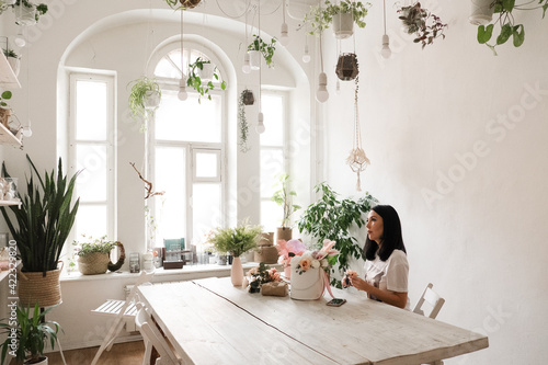 florist work brunette girl and a bouquet of flowers on the table in a stylish room