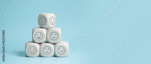 world mental health day concept or feedback rating and positive customer review, wood cube stacking with emotion face icon on blue background photo