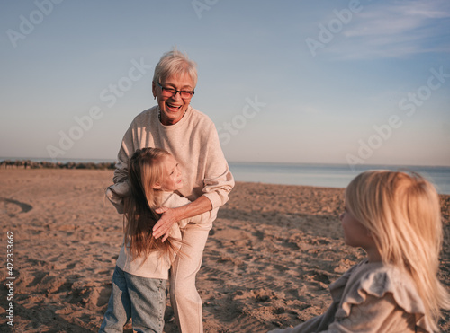 Grandmother plays with granddaughters on the shore photo