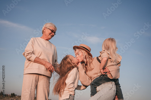 Young mother with daughters and grandmother together in nature
