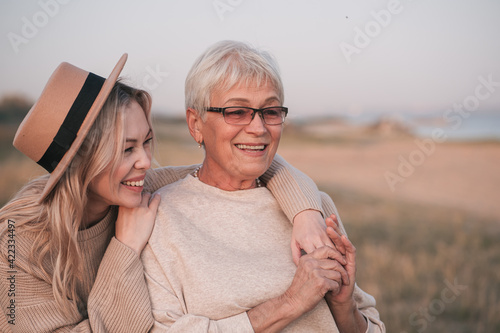 Adult daughter hugs her elderly mother in nature