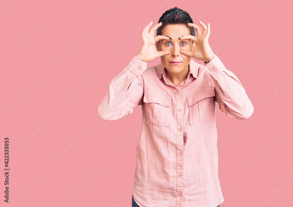 Young woman with short hair wearing casual clothes trying to open eyes with fingers, sleepy and tired for morning fatigue Young woman with short hair wearing casual clothes trying to open eyes with fingers, sleepy and tired for morning fatigue