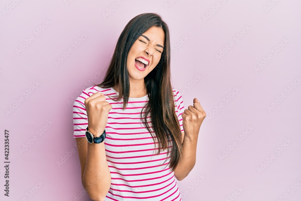 Young brunette woman wearing casual clothes over pink background celebrating surprised and amazed for success with arms raised and eyes closed. winner concept. Young brunette woman wearing casual clothes over pink background celebrating surprised and amazed for success with arms raised and eyes closed. winner concept.