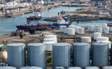 Aerial view of an oil tanker moored at an oil storage silo terminal port.