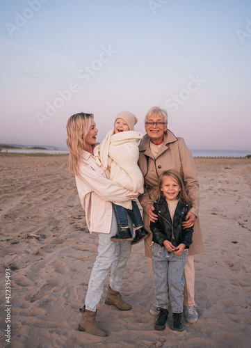 Happy family of mother and grandmother with children together on the beach