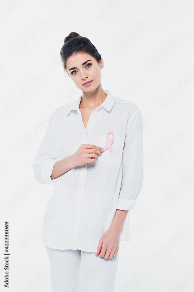 Young woman with pink ribbon of breast cancer awareness looking at camera isolated on white Young woman with pink ribbon of breast cancer awareness looking at camera isolated on white