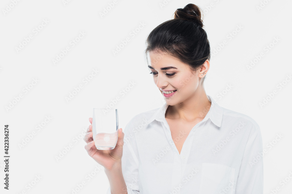 Young woman smiling and looking at glass of water isolated on white Young woman smiling and looking at glass of water isolated on white