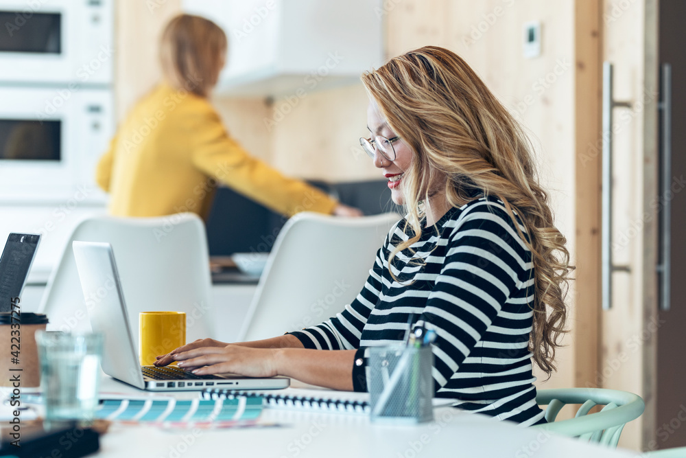Smiling asian business woman working and typing with laptop in coworking place. Smiling asian business woman working and typing with laptop in coworking place.