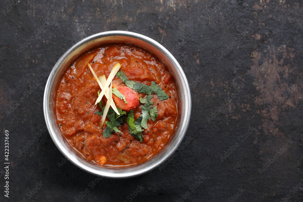 Top view of a vindaloo, curry, an oriental dish, on black stony background. Traditional Indian cuisine. Sauce based on pumpkin puree, tomato, meat or fish, with coriander, close-up with a copyspace. Top view of a vindaloo, curry, an oriental dish, on black stony background. Traditional Indian cuisine. Sauce based on pumpkin puree, tomato, meat or fish, with coriander, close-up with a copyspace.