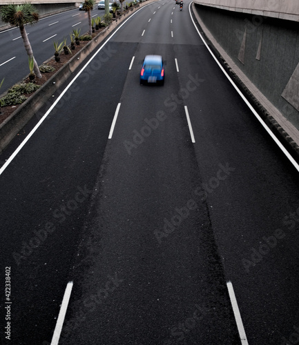 A blue car in movement on a black asplalt road  light trails and intentional movement zoom effect.