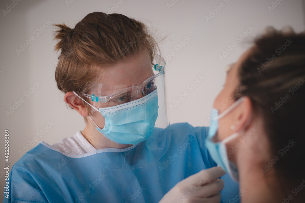 doctor in a sterile and protective suit takes a sample to assess positivity at the collection center. Swab from the patient's nose. Girl in a red T-shirt on a coronavirus test doctor in a sterile and protective suit takes a sample to assess positivity at the collection center. Swab from the patient's nose. Girl in a red T-shirt on a coronavirus test