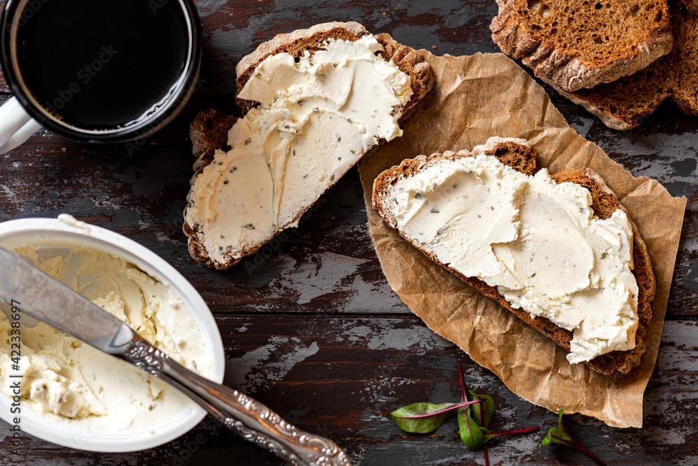 Rustic breakfast. Sandwich with soft cheese and rye bread on a dark wooden background top view. Ricotta sandwich and coffee. Rustic breakfast. Sandwich with soft cheese and rye bread on a dark wooden background top view. Ricotta sandwich and coffee.