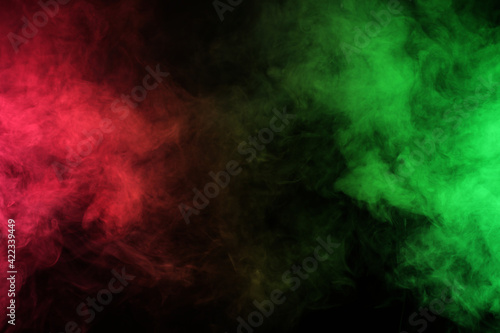 Smoke in red-green light on black background in darkness