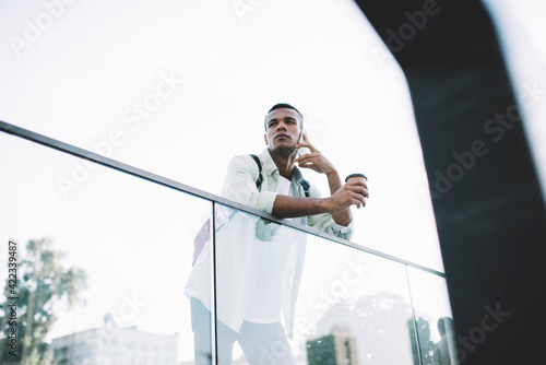 Black man talking on cellphone with coffee cup in street