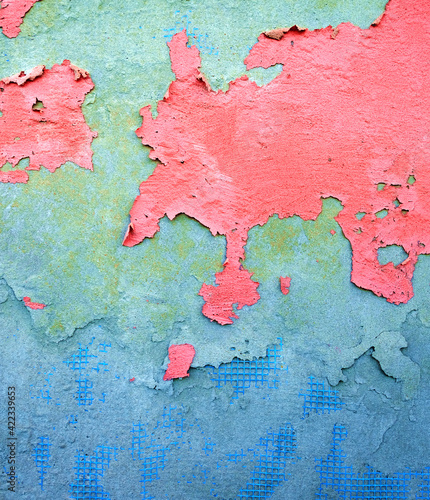 Pink flaking paint on blue and gray wall.