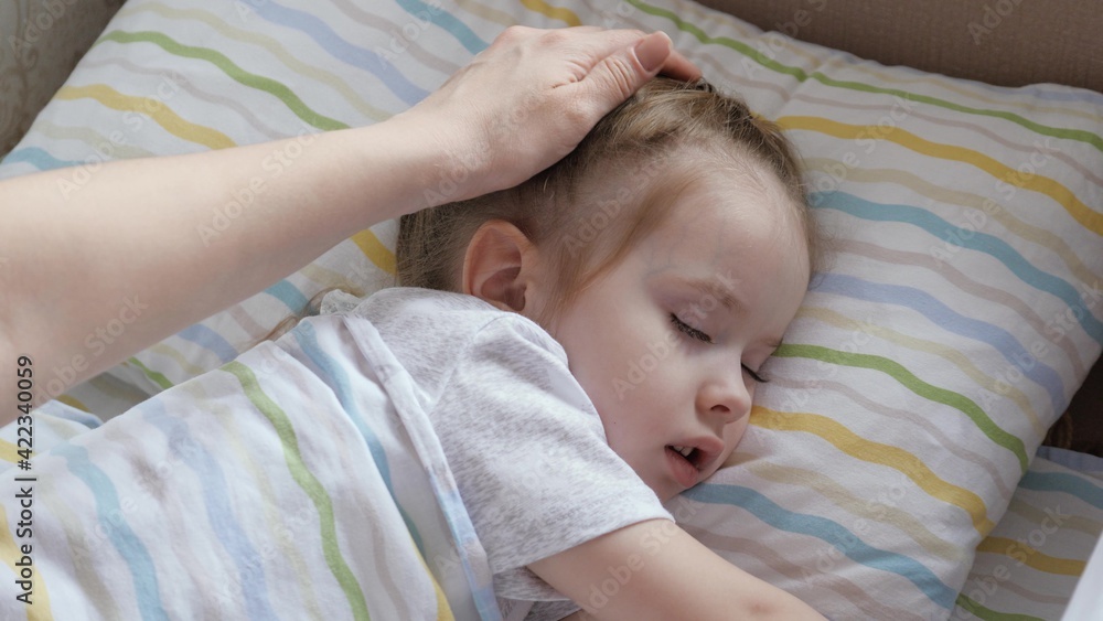 Happy baby sleeping in a crib mom covers baby with a blanket. Mom put