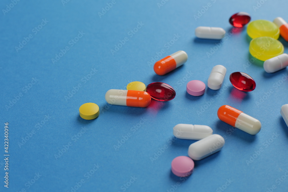 Multicolored medical pills of various shapes on a blue background Multicolored medical pills of various shapes on a blue background