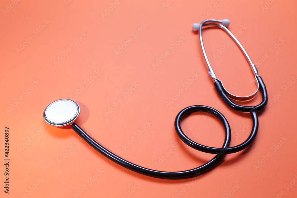 Blue medical stethoscope on orange background. Close-up Blue medical stethoscope on orange background. Close-up