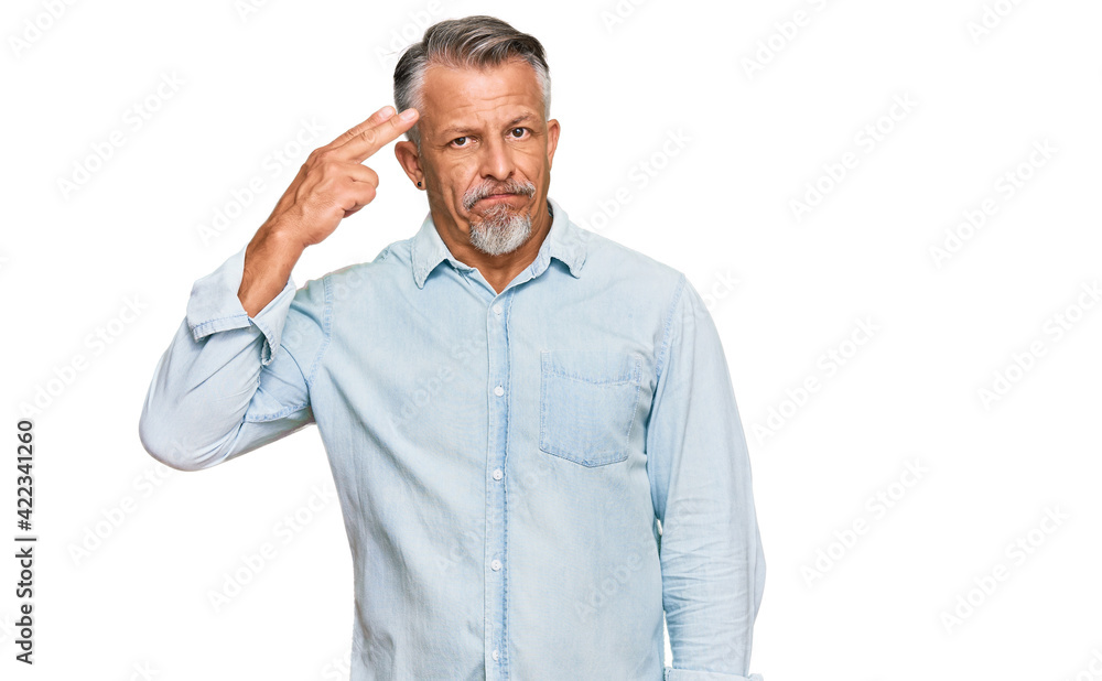 Middle age grey-haired man wearing casual clothes shooting and killing oneself pointing hand and fingers to head like gun, suicide gesture. Middle age grey-haired man wearing casual clothes shooting and killing oneself pointing hand and fingers to head like gun, suicide gesture.