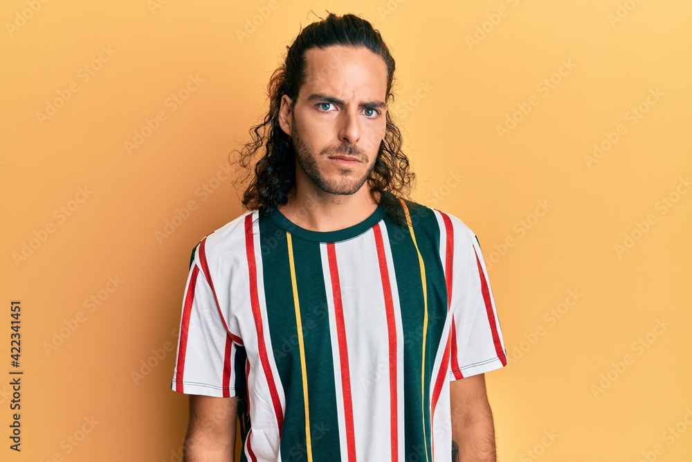 Young handsome man with long hair wearing casual clothes skeptic and nervous, frowning upset because of problem. negative person. Young handsome man with long hair wearing casual clothes skeptic and nervous, frowning upset because of problem. negative person.