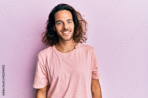 Young handsome man with long hair wearing casual clothes with a happy and cool smile on face. lucky person.