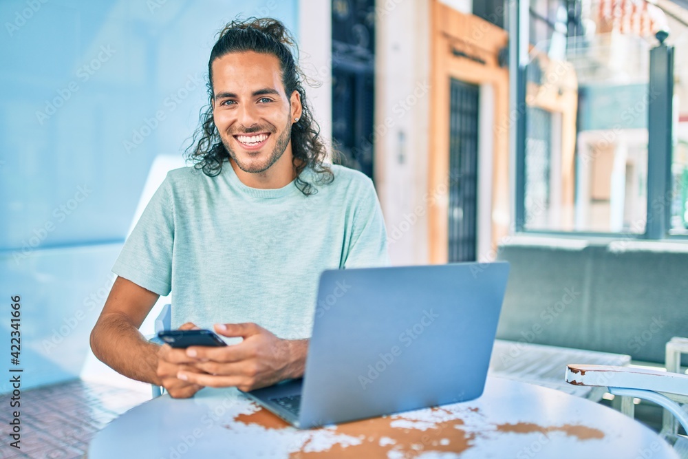 Young hispanic man smiling happy working using laptop at terrace of coffee shop. Young hispanic man smiling happy working using laptop at terrace of coffee shop.