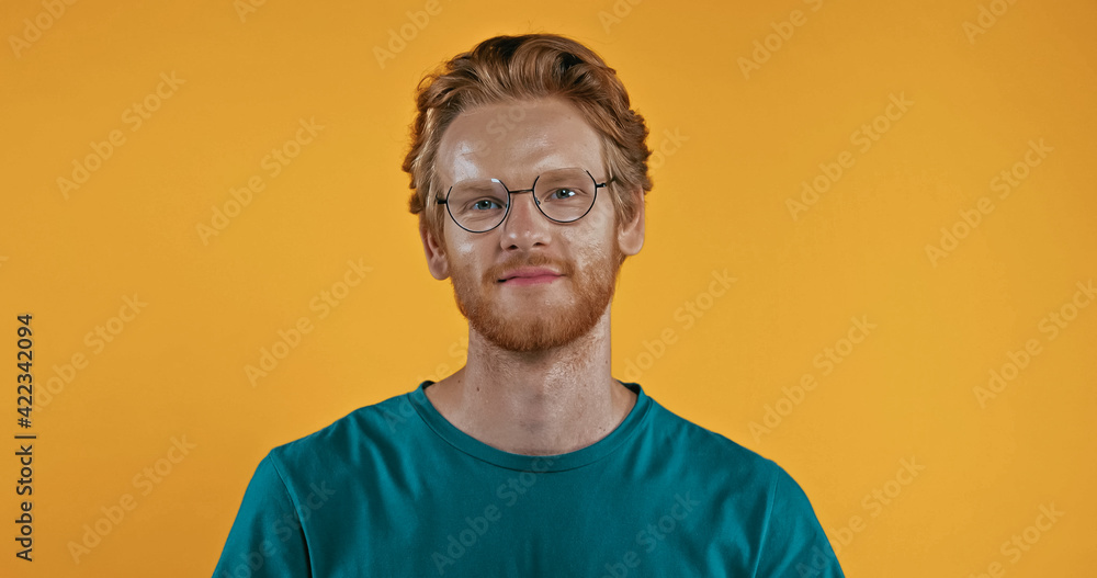 positive redhead man in glasses looking at camera isolated on yellow positive redhead man in glasses looking at camera isolated on yellow