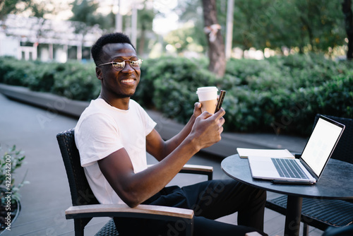 Cheerful African American man sitting with phone and coffee © BullRun
