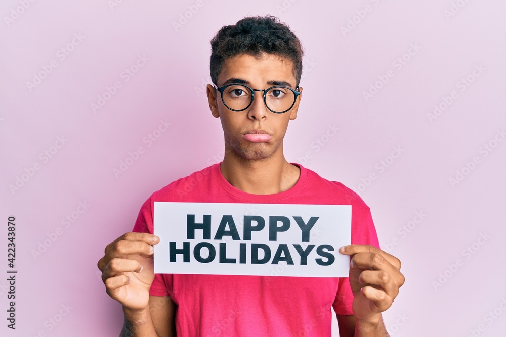 Young handsome african american man holding happy holidays message depressed and worry for distress, crying angry and afraid. sad expression. Young handsome african american man holding happy holidays message depressed and worry for distress, crying angry and afraid. sad expression.