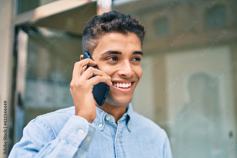 Young latin man smiling happy talking on the smartphone walking at the city. Young latin man smiling happy talking on the smartphone walking at the city.